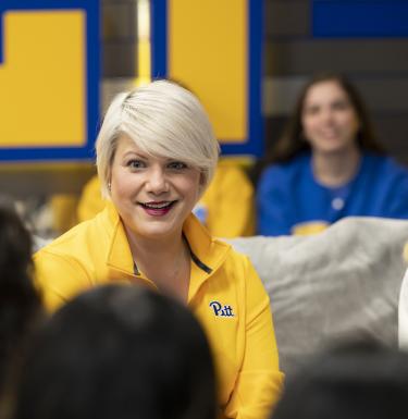 A woman with short blonde hair in a yellow quarter zip.