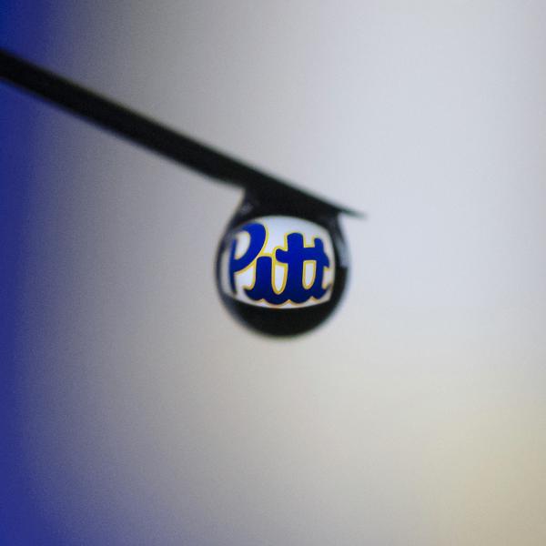 Silhouette of a syringe needle with a drop of water.