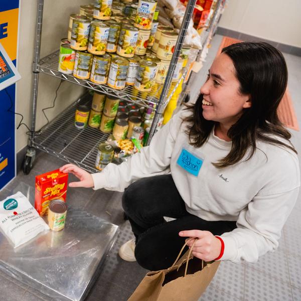 A female student weighing food on a scale in the Pitt Pantry.