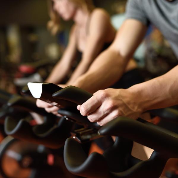 Hands grasping stationary bike handles.