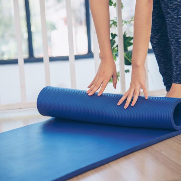 Hands rolling up a blue yoga mat.