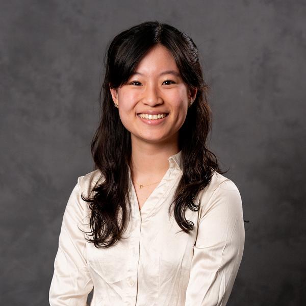 Woman with long dark hair smiling in a white button down blouse.