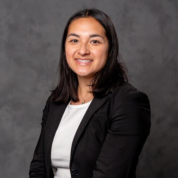 A woman with short dark hair smiling in a black suit.