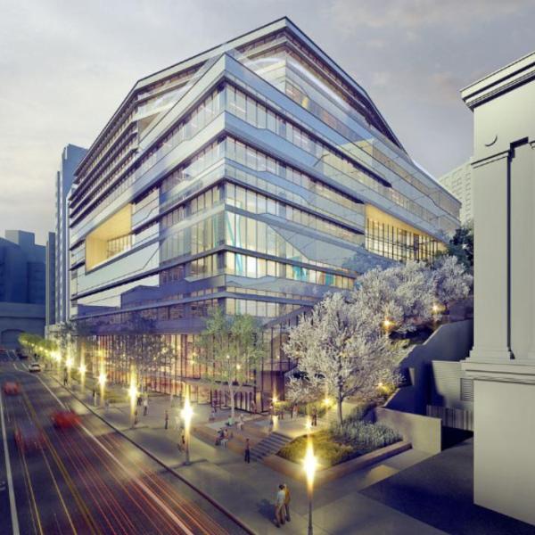 Realistic model of a futuristic 9-story glass building in a city spotted with warm lights and plants.