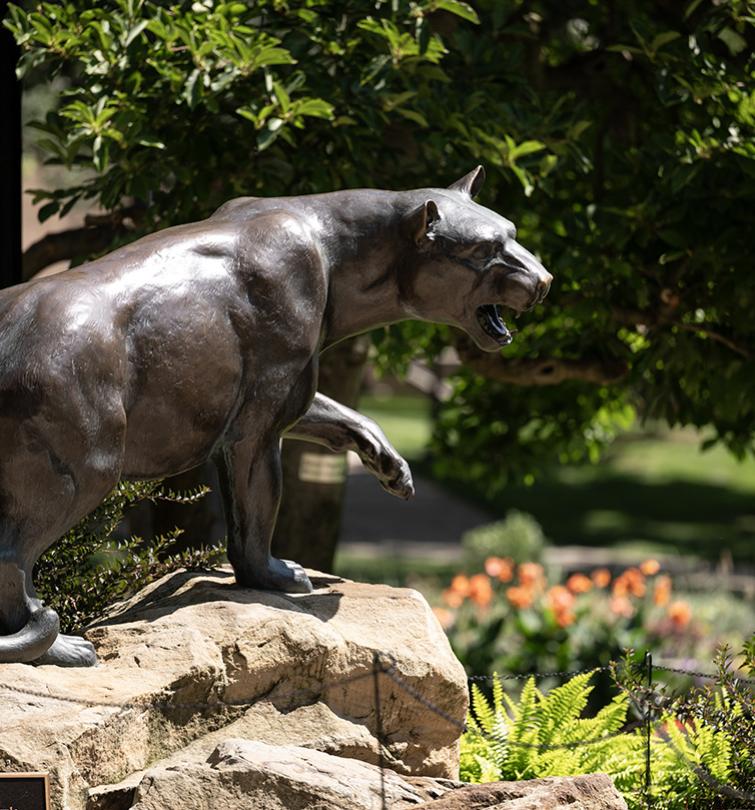 The bronze Panther statue in the summer surrounded by greenery.