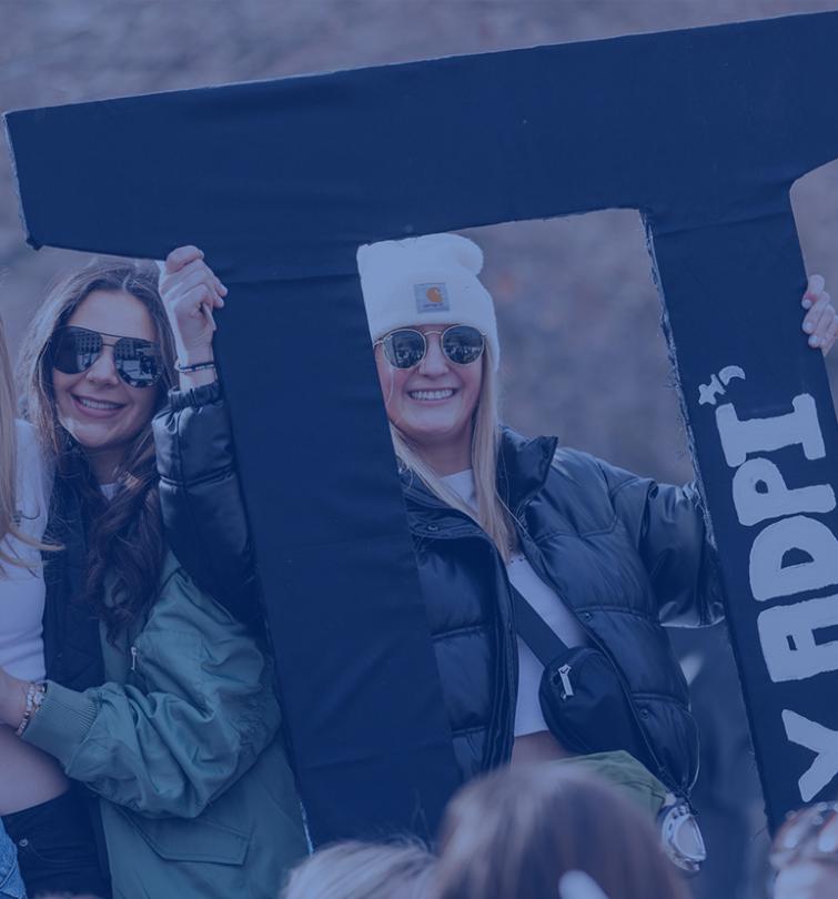 Two students in sunglasses holding large Greek letters.