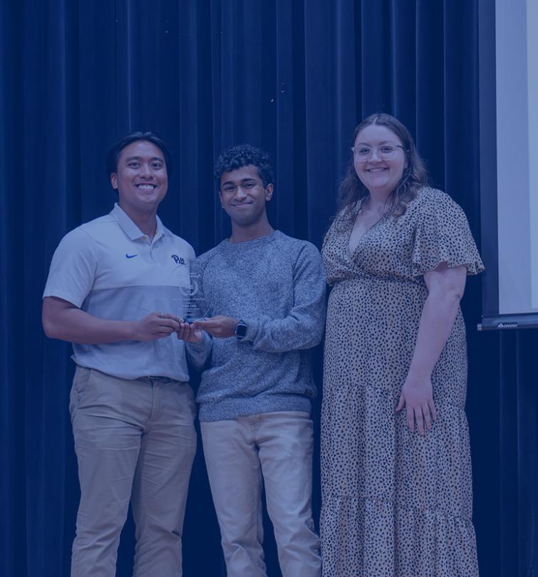Three adults standing on a stage.
