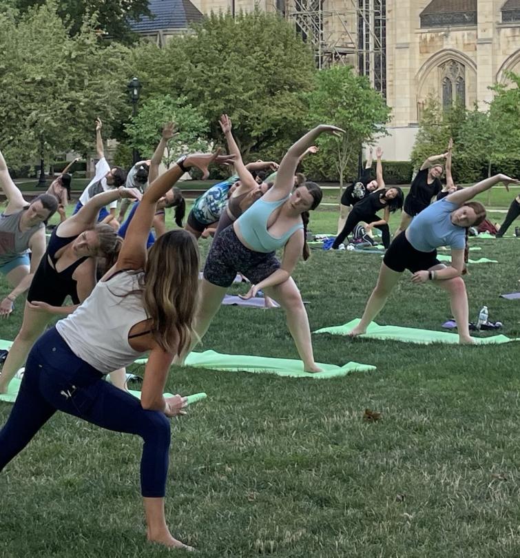 A group of students do yoga outdoors.