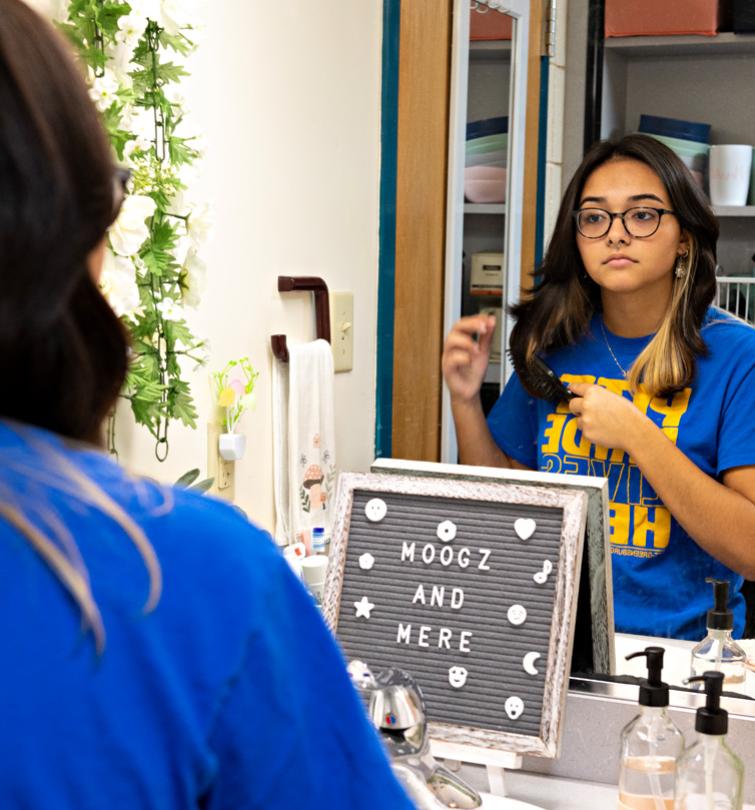 Student looking in a dorm mirror.