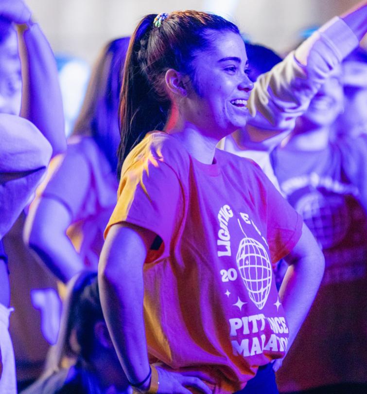 Student smiling at a colorfully-lit indoor event.