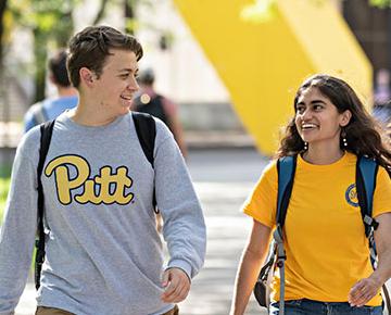 Two students walk and smile on campus.