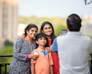 Family of three having their photo taken outside.