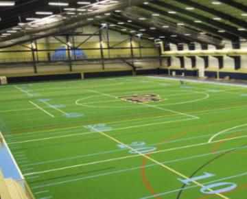 An indoor green turfgrass football field.