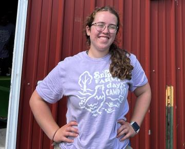 Young woman smiling in front of barn.