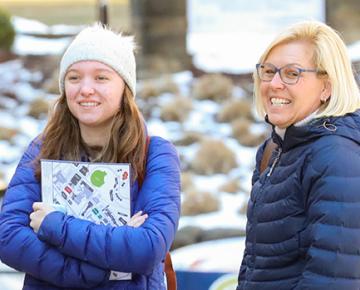 A student and her parent standing outside.