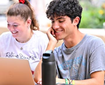 Students together looking at a laptop.