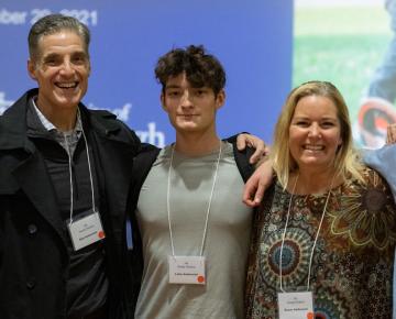 Five people in lanyards smile and pose for a photo indoors.