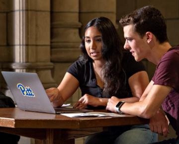 Students working and looking at a laptop.