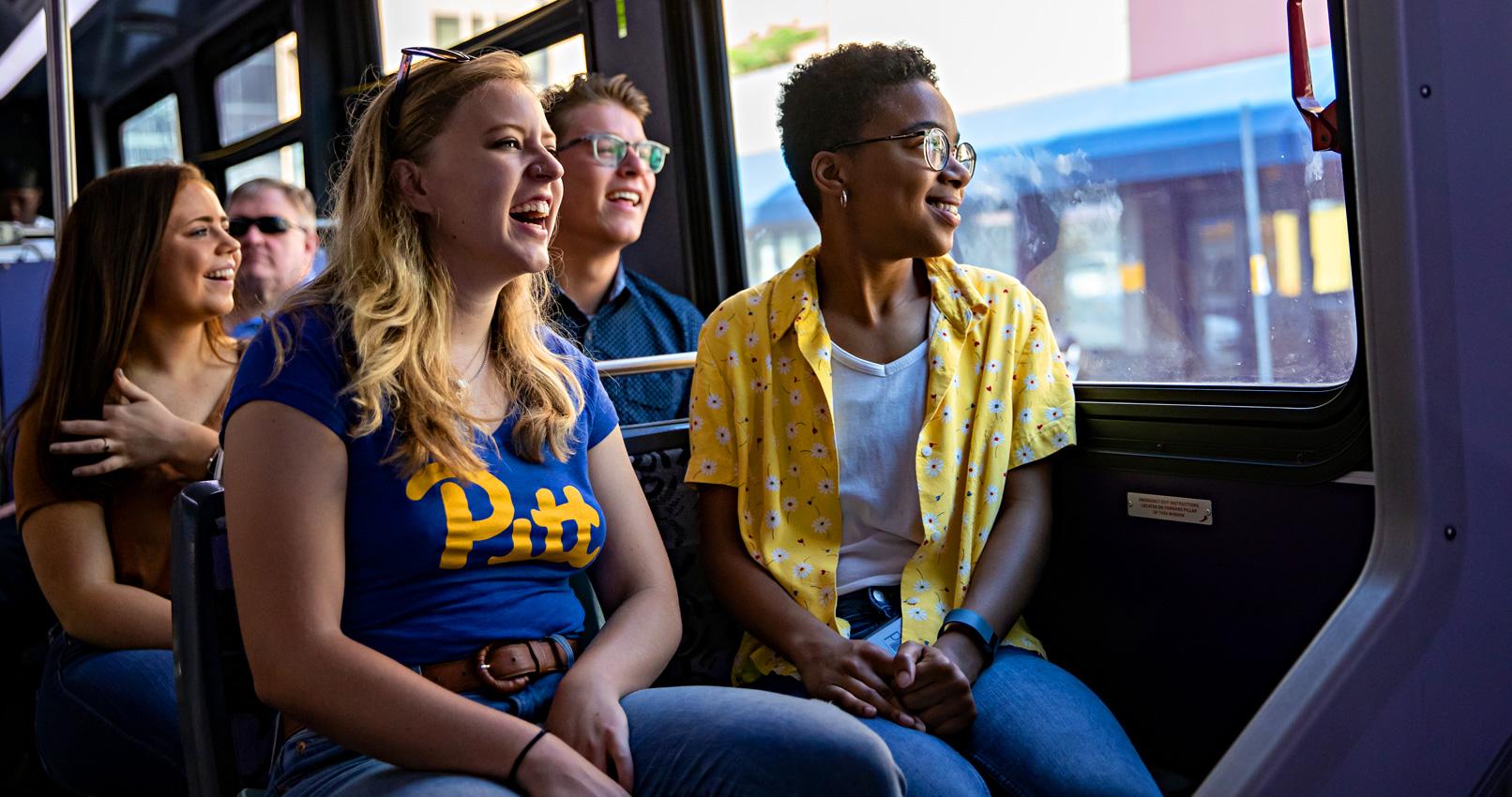 Students smiling sitting on bus looking out window