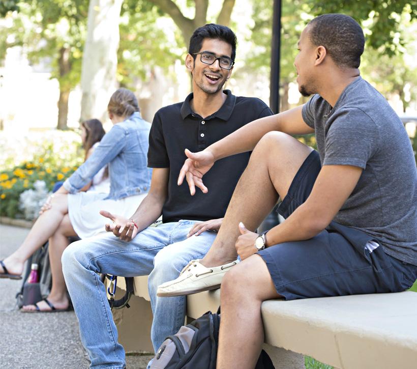 Students sitting on a bench outside.