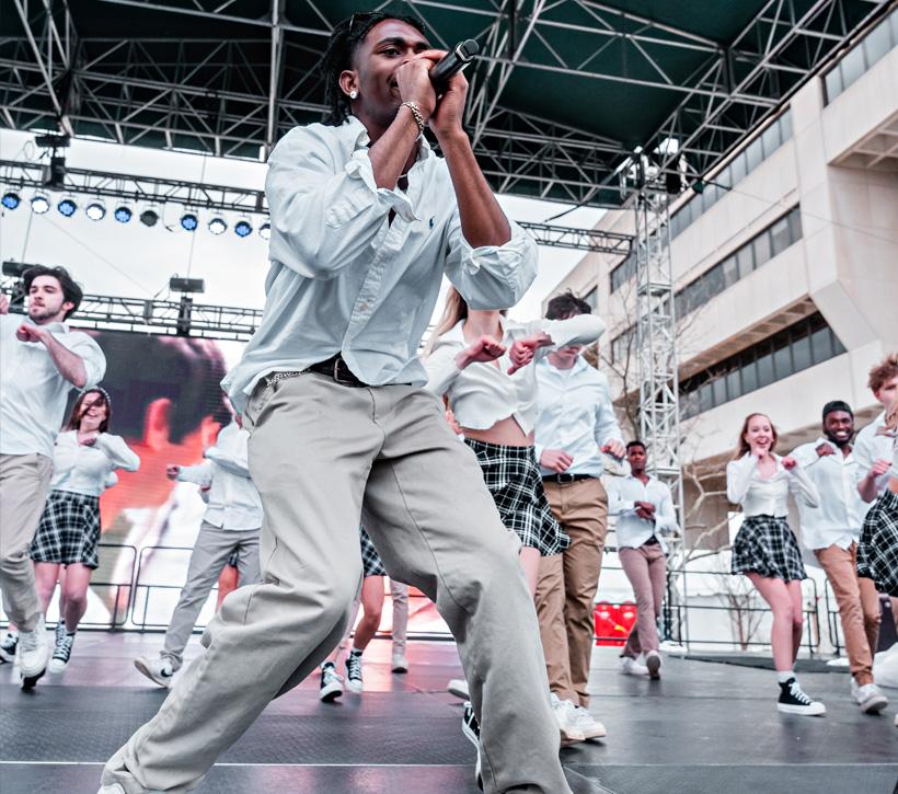 Students performing on stage singing in matching outfits.