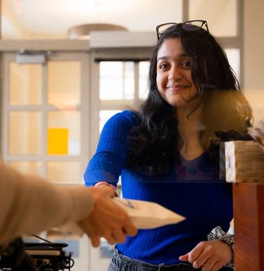 Woman accepting a white paper bag from a pharmacist counter.