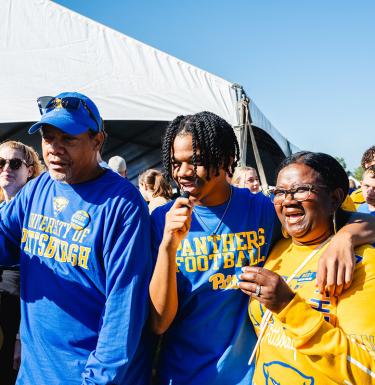 A family of three laughing at a tailgate event.