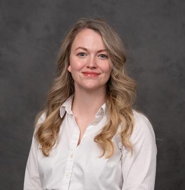 A woma with long blonde hair smiling in a white top.