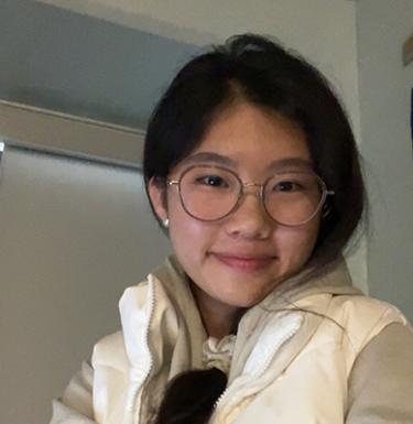 A woman in glasses with dark hair smiling