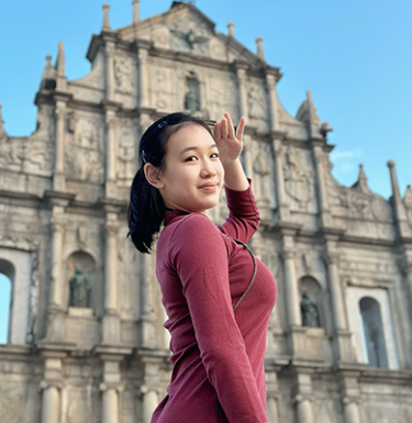 A photo of a woman with dark hair in a red top smiling.