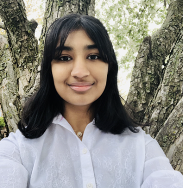 Photo of a woman with dark hair smiling in a white button down shirt.