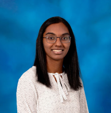 Headshot of a smiling woman in a white shirt and square glasses on a blue background.