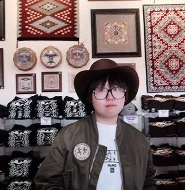 A woman with short dark hair in a cowboy hat and green jacket