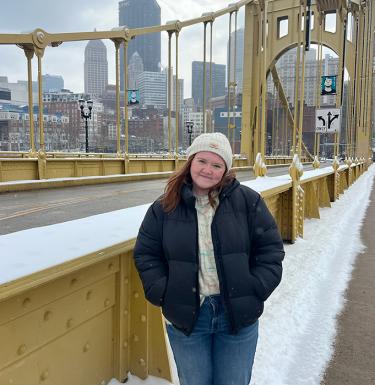 A woman with long hair standing on a snowy yellow bridge.