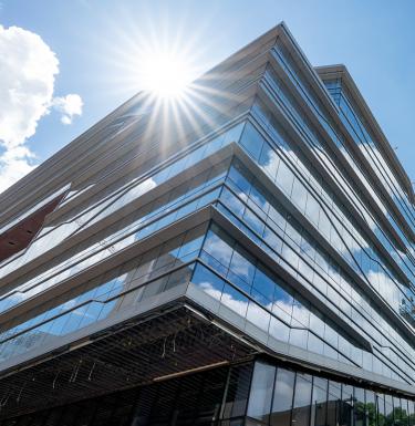 An angular building full of windows reflecting the sun.