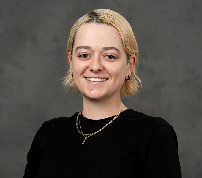 Blonde woman with short hair in a black short sleeve top.