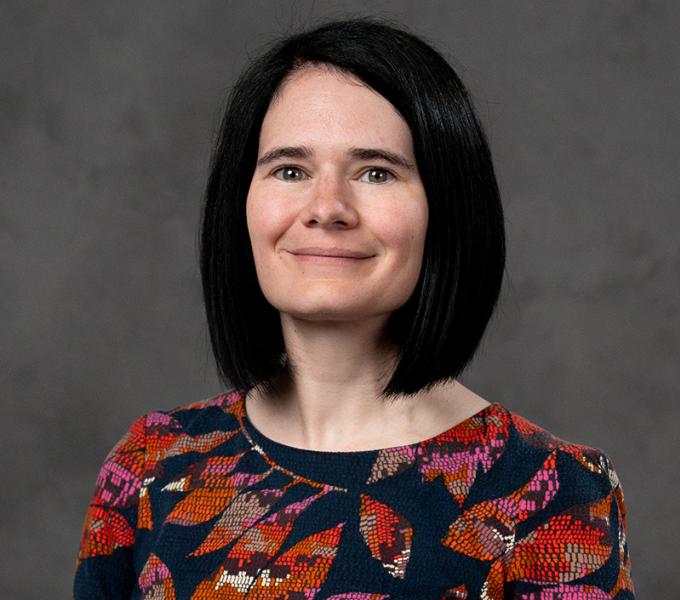 Woman with short dark hair in a dark floral top.