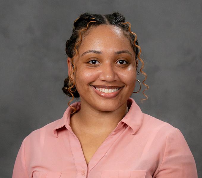 A woman smiling in a pink button up top.