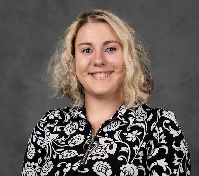 Woman with blonde hair in a short sleeve black and white floral blouse.