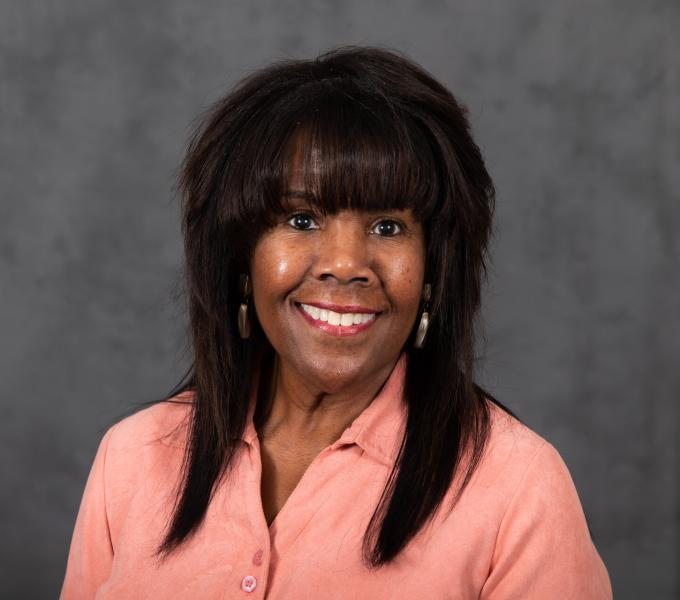 Headshot of smiling woman in salmon shirt.