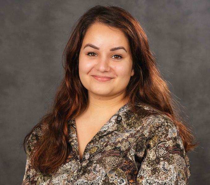 Headshot of a smiling woman with reddish-brown hair and a paisley-print shirt.