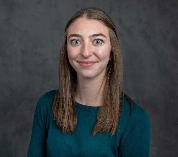 Headshot of young woman with straight light brown hair in a turquoise shirt.