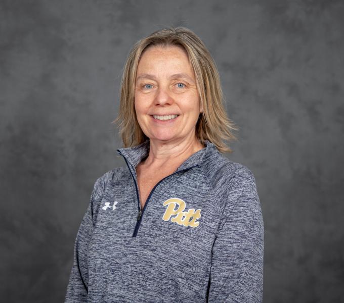 Headshot of a smiling blonds woman in a gray quarter zip Pitt branded sweatshirt.