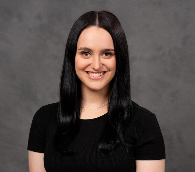 A woman with long dark hair smiling in a black tshirt.