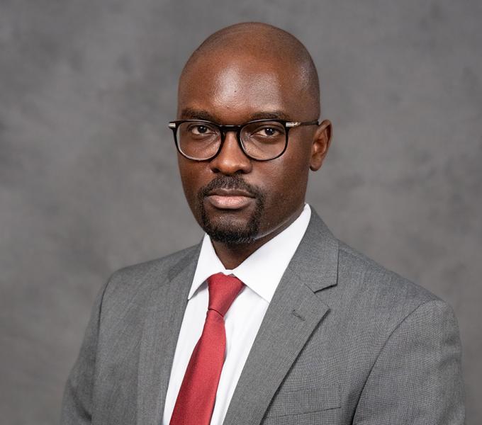 A bald man with glasses in a grey suit.