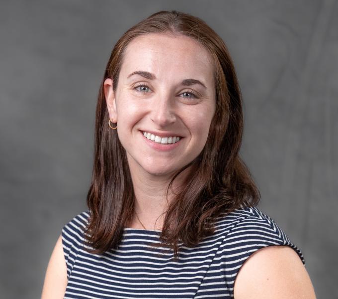 Headshot of smiling brunette woman in hoop earrings and a Breton stripe shirt.