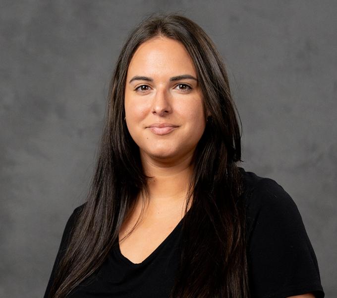 Photo of a woman with long dark hair in a black v-neck tshirt.