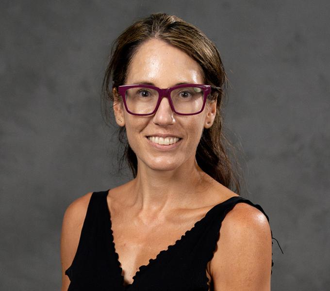 Photo of a woman with long dark hair in a black v-neck shirt.