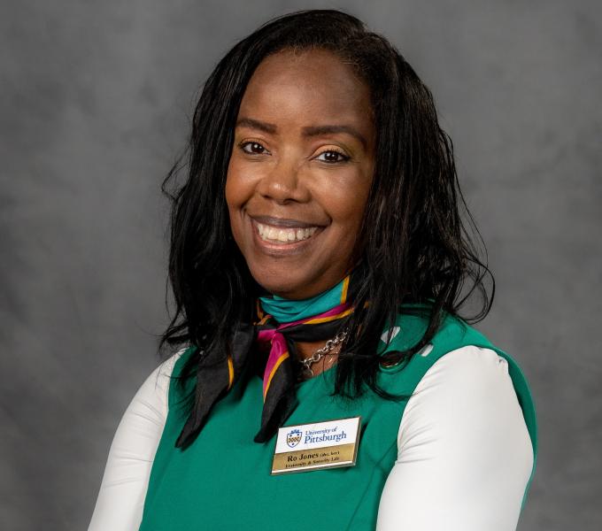 Headshot of a smiling woman in a white shirt, green top, and small silk scarf.