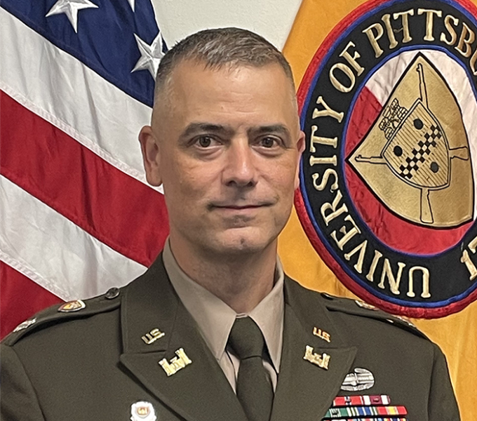 A man in a military uniform in front of a flag.